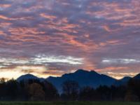 Morgenstimmung mit verzerrten orangerot leuchtenden Wolken über den Bergen